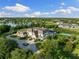 Expansive aerial view of an estate home with lush landscaping, a lake, and a tennis court under a bright blue sky at 18521 Wayne Rd, Odessa, FL 33556