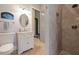 A bright bathroom features a single sink vanity, stone-tiled floors, a walk-in shower, and a unique 'Looney Bin' sign at 18521 Wayne Rd, Odessa, FL 33556