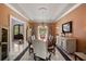 This elegant dining room features a long wood table, marble flooring, a chandelier, crown molding, and salmon-colored walls at 18521 Wayne Rd, Odessa, FL 33556