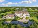 Aerial view of a stately home with lush landscaping, circular driveway, a water fountain, and mature trees at 18521 Wayne Rd, Odessa, FL 33556
