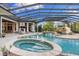 A luxurious covered pool area with a waterfall, slide, hot tub, and an outdoor fireplace makes for a perfect Gathering entertainment space at 18521 Wayne Rd, Odessa, FL 33556