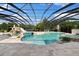 A large screened-in pool features a rock waterfall and slide, complete with an attached spa at 18521 Wayne Rd, Odessa, FL 33556