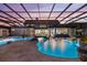 The illuminated custom pool and spa area with waterfall and slide are enclosed in a screened lanai at 18521 Wayne Rd, Odessa, FL 33556
