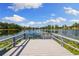 Scenic waterfront view with a private dock and serene water lilies under a blue sky with fluffy clouds at 18521 Wayne Rd, Odessa, FL 33556