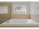 Bright bathroom featuring a soaking tub with a decorative window and tiled surround at 19206 Ivy Oak Way, Tampa, FL 33647
