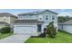 Charming two-story blue house with an attached garage, featuring solar panels and a neatly landscaped front yard at 2073 Branding Iron Way, New Port Richey, FL 34655