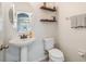 Well-lit powder room with pedestal sink, decorative shelves, and a towel rack for convenience at 2073 Branding Iron Way, New Port Richey, FL 34655