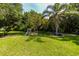Spacious backyard with lush landscaping, palm tree, and swing set at 22442 Vale Ave, Punta Gorda, FL 33980