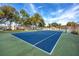 Community tennis court with blue surface, surrounded by lush greenery and trees at 2400 Winding Creek Blvd # Bldg18A210, Clearwater, FL 33761
