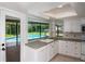 Kitchen sink and countertop featuring tile floors, white cabinets, with a view of the screened-in pool at 2532 Sweetgum W Way, Clearwater, FL 33761