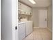 Well-lit laundry room featuring tile floors, washer, dryer, cabinets, sink, and access door at 2532 Sweetgum W Way, Clearwater, FL 33761