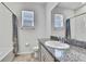 Well-lit bathroom with granite countertop vanity, white cabinets and full size mirror at 31105 Mango Fade Way, San Antonio, FL 33576