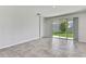 A modern living room featuring neutral tile floors, white walls, and a sliding glass door to the yard at 31105 Mango Fade Way, San Antonio, FL 33576