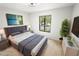Staged bedroom offering wood floors, an oversized window and a grey upholstered bed at 3232 Lake Pine E Way # A2, Tarpon Springs, FL 34688