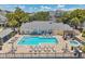 Community pool with lounge chairs and outdoor tables with a partial view of a person swimming at 3301 Haviland Ct # 301, Palm Harbor, FL 34684