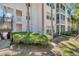 Rear exterior of building featuring porch and stairs, surrounded by lush landscaping at 3301 Haviland Ct # 301, Palm Harbor, FL 34684