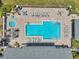 Aerial view of community pool with lounge chairs, tables, and a hot tub surrounded by brick pavers at 3301 Haviland Ct # 301, Palm Harbor, FL 34684