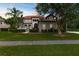 Charming home featuring a well-manicured lawn, tropical landscaping, and inviting arched entryway at 3500 Ballastone Dr, Land O Lakes, FL 34638