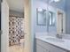 Bright bathroom with a marble countertop sink, large mirror, and a shower/tub featuring a unique patterned curtain at 3603 Arbor Chase Dr, Palm Harbor, FL 34683