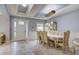 Dining room featuring tile floors, tray ceiling, elegant furniture, and a view of the front door at 3603 Arbor Chase Dr, Palm Harbor, FL 34683