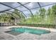 Beautiful screened pool with a sun shelf and stone pavers with lush greenery at 3603 Arbor Chase Dr, Palm Harbor, FL 34683
