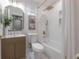 Bright bathroom with a tiled shower/tub, unique light fixtures, patterned wood vanity and marble flooring at 3811 N Arlington Ave, Tampa, FL 33603