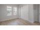 Bright bedroom featuring two windows, neutral walls, wood floors, and a closet with sliding doors at 3811 N Arlington Ave, Tampa, FL 33603