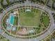 Aerial view of a park featuring community pool, playground, a large central lawn, and surrounding streets at 3833 Villamore Ln, Odessa, FL 33556