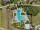 Aerial view of a community pool with lounge chairs, tables, umbrellas, and lush landscaping at 3833 Villamore Ln, Odessa, FL 33556