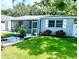 Inviting single-story home with lush lawn, white rock landscape features, and screened-in porch at 411 Locklie St, Dunedin, FL 34698