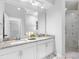 Bathroom featuring a double vanity with granite countertop and framed mirror, next to glass-enclosed shower at 4401 S Trask St, Tampa, FL 33611