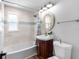 Well-lit bathroom featuring a bathtub with shower, updated vanity, and an oval mirror above the sink at 4401 S Trask St, Tampa, FL 33611
