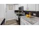 Well-lit kitchen with stainless steel appliances, granite counters, black backsplash, and white cabinetry at 4401 S Trask St, Tampa, FL 33611