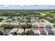 An aerial view features a peaceful neighborhood with homes, mature trees, and a serene highway in the distance at 4735 Red Pine Way, Wesley Chapel, FL 33545