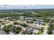 An aerial view showcases a community surrounded by lush landscapes, trees, and a water view in the distance at 4735 Red Pine Way, Wesley Chapel, FL 33545