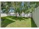 Fenced backyard with a grassy lawn and mature shade trees on a sunny day at 4735 Red Pine Way, Wesley Chapel, FL 33545