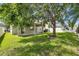 Fenced backyard with a grassy lawn, mature shade trees, and partial home view at 4735 Red Pine Way, Wesley Chapel, FL 33545