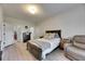 Bright bedroom has a queen bed, a dresser, and a leather armchair at 4735 Red Pine Way, Wesley Chapel, FL 33545