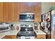 Close up of kitchen featuring stainless steel microwave and range, and natural wood cabinets at 4735 Red Pine Way, Wesley Chapel, FL 33545