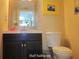 Well-maintained bathroom featuring a dark vanity, toilet, and decorative mirror and art at 5139 Corvette Dr, Tampa, FL 33624