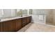 Elegant bathroom featuring double sinks, granite countertops, wood cabinets, and tiled floors at 6035 Nikki Ln, Odessa, FL 33556