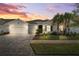 Charming single-story home with a brick driveway, two-car garage and manicured lawn with palm trees under a colorful sunset at 6035 Nikki Ln, Odessa, FL 33556