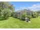 View of the backyard with lush green grass and a screen enclosed patio surrounded by landscaping at 6041 Sandhill Ridge Dr, Lithia, FL 33547