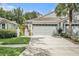 Front exterior featuring a large garage, palm tree, decorative landscaping, and a well maintained yard at 6041 Sandhill Ridge Dr, Lithia, FL 33547