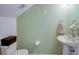 Well-lit half bath with a pedestal sink, green wall, and neutral accents offering a fresh, minimalist design at 637 Kensington Lake Cir, Brandon, FL 33511