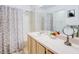 Well-lit bathroom showcases a shower-tub combo, patterned shower curtain, vanity, and mirror, creating a functional space at 637 Kensington Lake Cir, Brandon, FL 33511