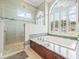 Elegant bathroom featuring a soaking tub with jets, walk-in shower, and large windows with stylish shutters at 6905 Arabian Rd, Odessa, FL 33556
