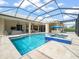 Relaxing screened in pool area with an in-ground spa, outdoor furniture, and a beautiful clear swimming pool at 6905 Arabian Rd, Odessa, FL 33556