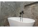 Freestanding tub in bathroom featuring marble tiling and black fixtures at 711 42Nd S Ave, St Petersburg, FL 33705