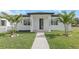 A charming home features a walkway leading to the front door, a lush lawn, and palm trees adding to the curb appeal at 711 42Nd S Ave, St Petersburg, FL 33705